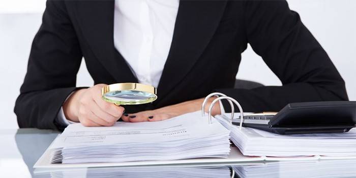 Mujer estudiando documentos a través de una lupa