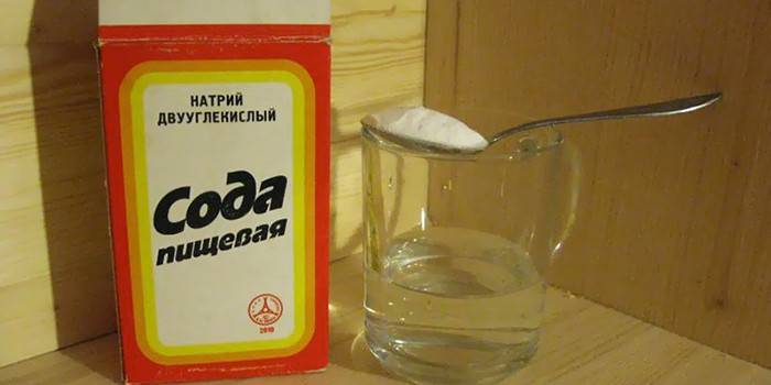 Pakuotė sodos, šaukštas su soda ir puodelis vandens