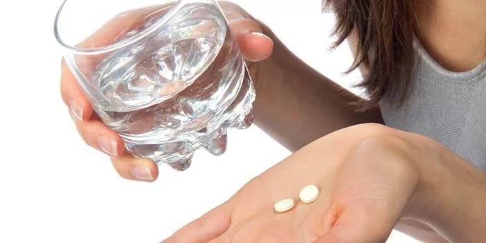Người phụ nữ cầm ly nước và thuốc trong tay