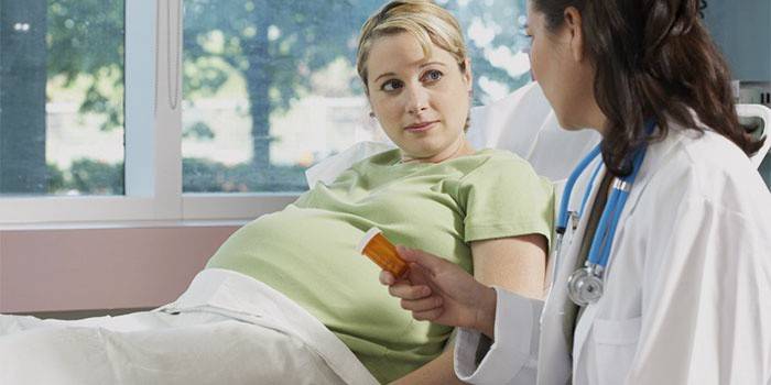 Medicul îi oferă unei femei însărcinate un borcan cu pastile