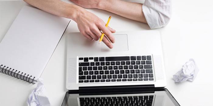 Homme avec un crayon et un cahier sur un ordinateur portable