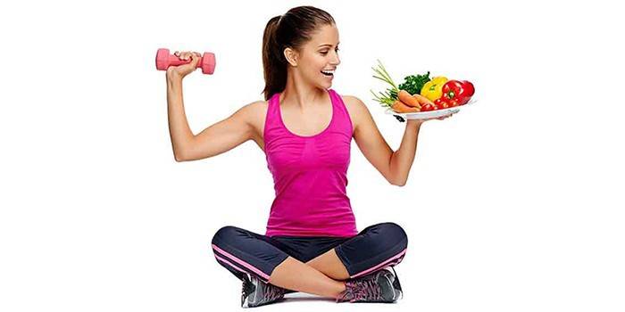 Cô gái cầm quả tạ và một đĩa rau trong tay