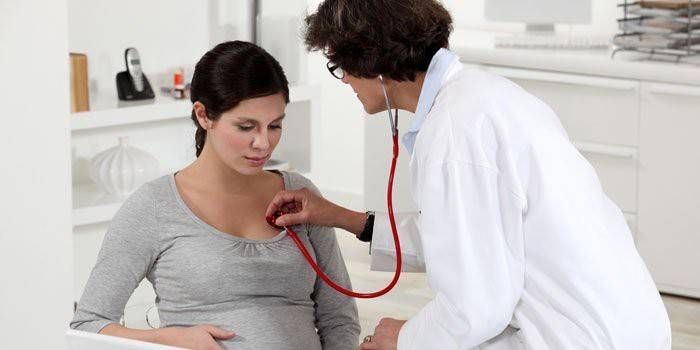 Doctorul ascultă plămânii unei femei însărcinate