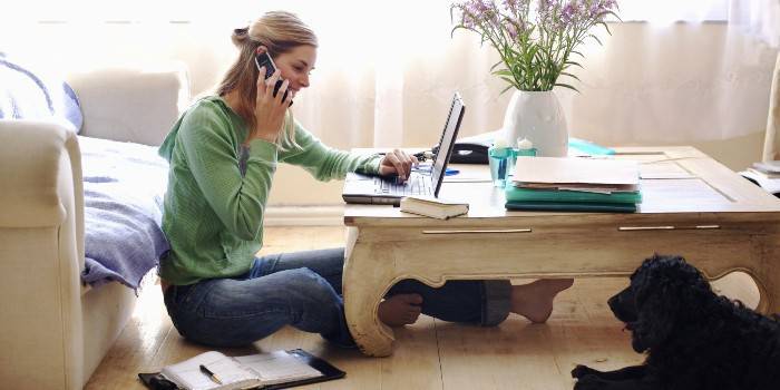 La fille à l'ordinateur portable parle au téléphone
