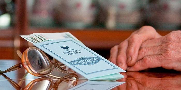 Para, gözlük ve yaşlı bir adamın elleri ile hesap cüzdanı