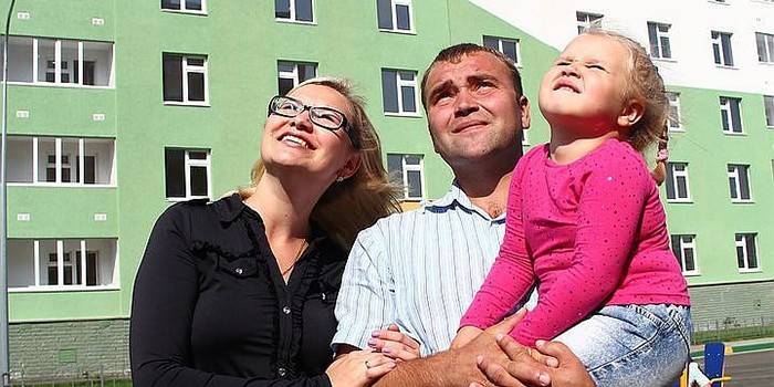 Млада породица у позадини нове зграде