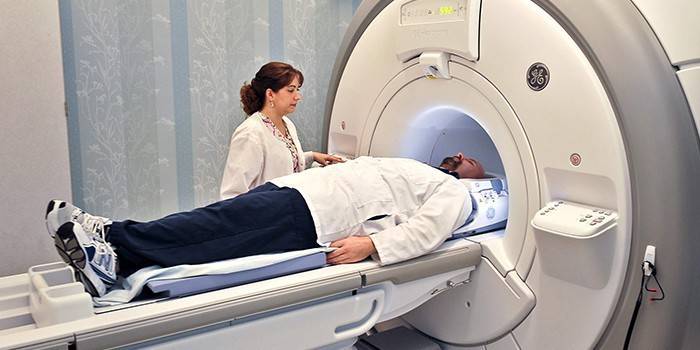 En mann i et computertomografiapparat og en lege i nærheten