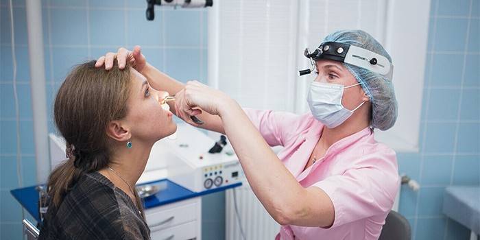 Medicul examinează nasul pacientului