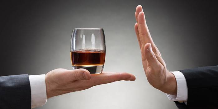 Un hombre rechaza un vaso de alcohol.
