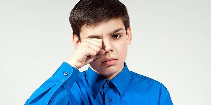 Il ragazzo si strofina gli occhi con il pugno