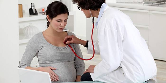 Legen lytter til lungene til en gravid kvinne med et fonendoskop
