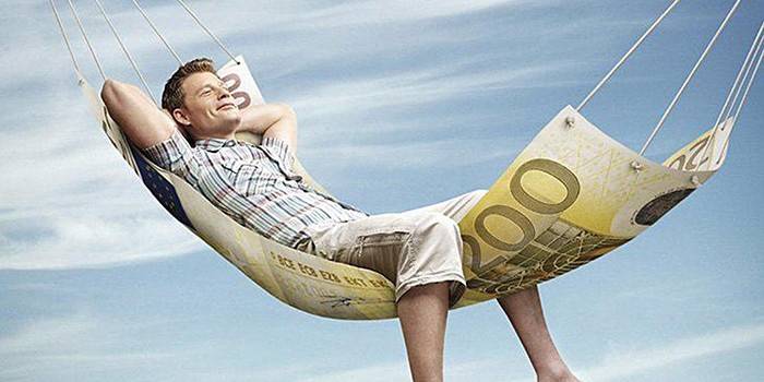 Egy ember függőágyban fekszik, 100 eurós bankjegyből