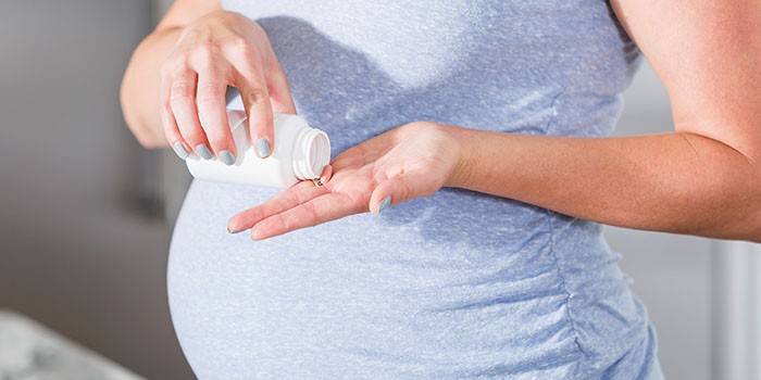 Bà bầu cầm một viên thuốc trong tay.