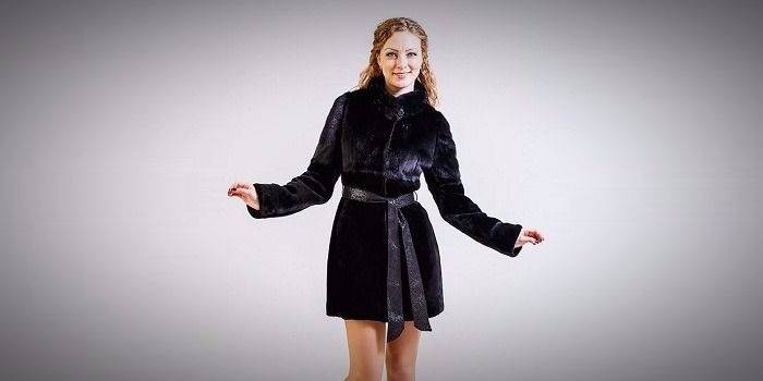 La fille dans un manteau de fourrure court d'un vison et un muton