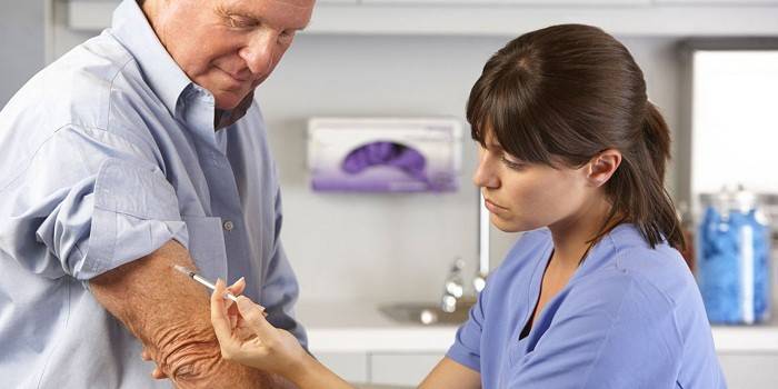 Medic face o injecție în mâna unui bărbat