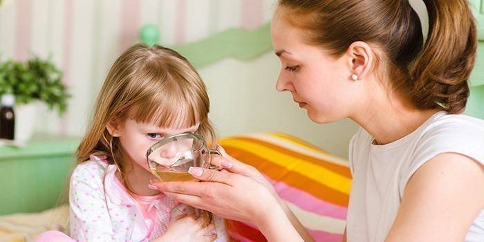 Moteris maitina savo vaiko vaistažolių sultinį