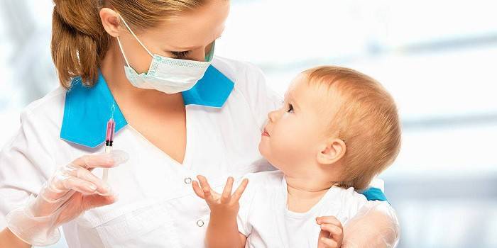 Medic are în mâini un copil și o seringă cu un medicament