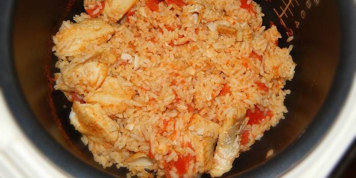 Pilaf com peixe e tomate em um fogão lento