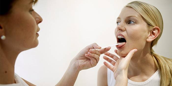 El doctor examina la garganta de una niña.
