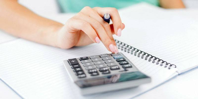 Mulher faz cálculos em uma calculadora