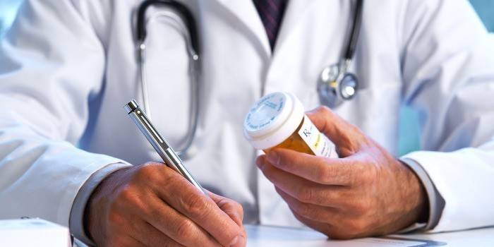 El doctor sostiene un bolígrafo y un paquete de píldoras.