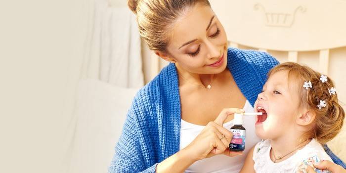 Mor irrigerer babyens hals med en spray Aqualor