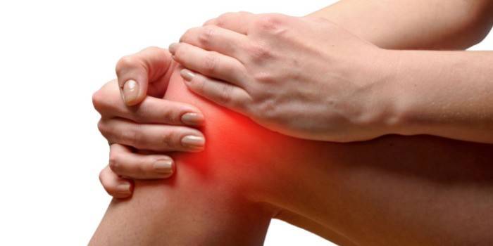 La mujer se aferra a la articulación de la rodilla dolorida.
