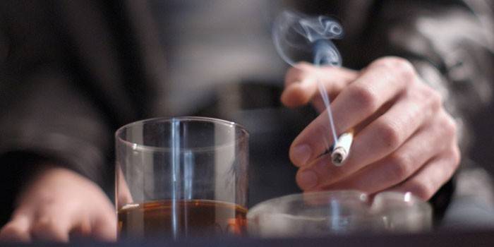 Vīrietis ar cigareti un glāzi alkohola