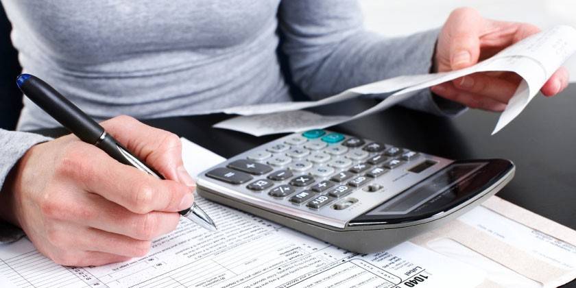 Calculadora, documentos e caneta em uma mão