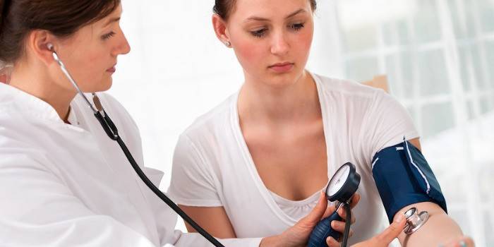 El médico mide la presión del paciente.